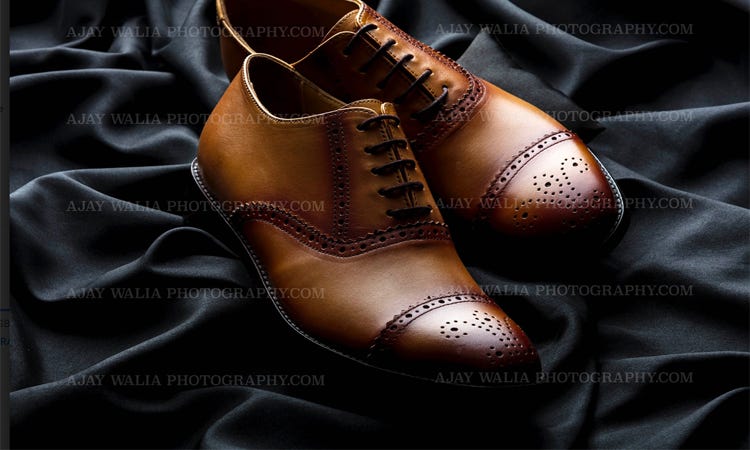 This is an aesthetically appealing photo of a pair of brown leather shoes against a stark white background. The shoes are expertly lit and photographed with a shallow depth of field, creating a soft focus on the shoes and background. The shoes are in pristine condition, and the careful attention to detail showcases the craftsmanship and beauty of the shoes. The photo is perfect for any store, website, or publication looking to draw attention to the quality of their shoes. Shoes Photography for Banner, Websites, Ecommerce by Ajay Walia